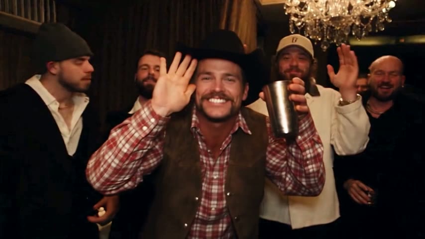 Cowboy with a horseshoe mustache and black hat waving a silver cup